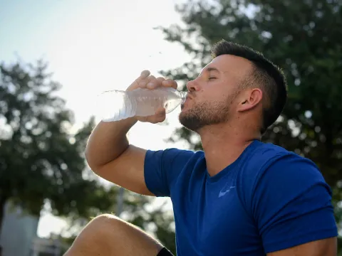 A young man drinking a water-bottle after exercising.