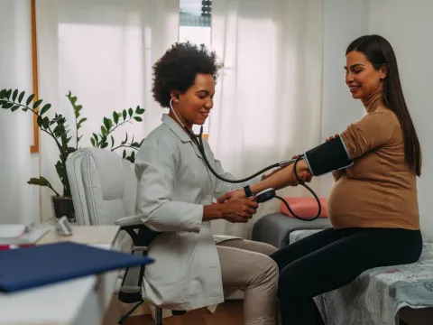 Pregnant woman getting her blood pressure checked by a physician