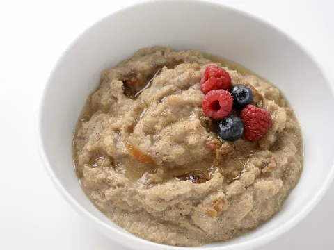bowl of cooked quinoa, topped with raspberries and blueberries