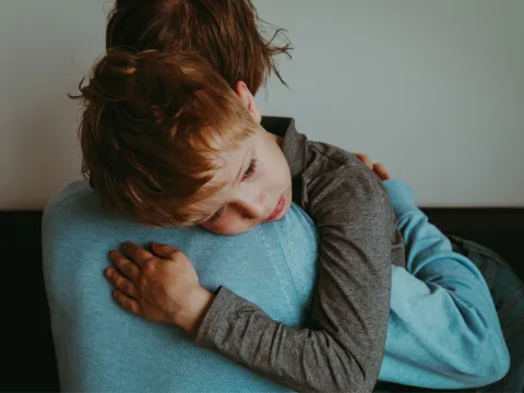 A mother holding and comforting her son.