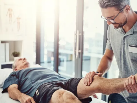Physical Therapist helping an older male patient with leg.