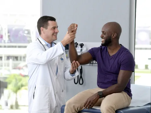 A Provider Checks a Patient's Elbow Joint in an Exam Room
