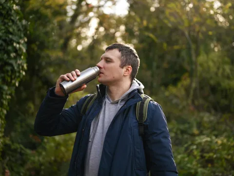 A man drinking water from a metal bottle.