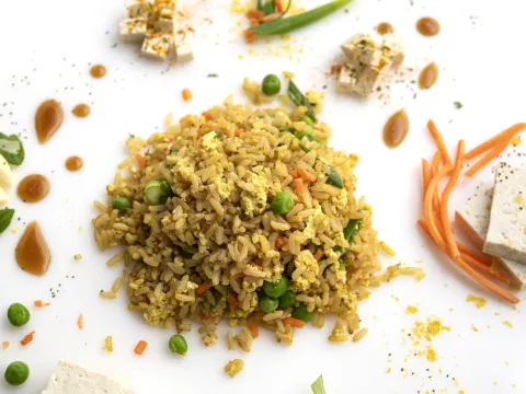 Mound of fried rice on white surface next to crackers and garnishes