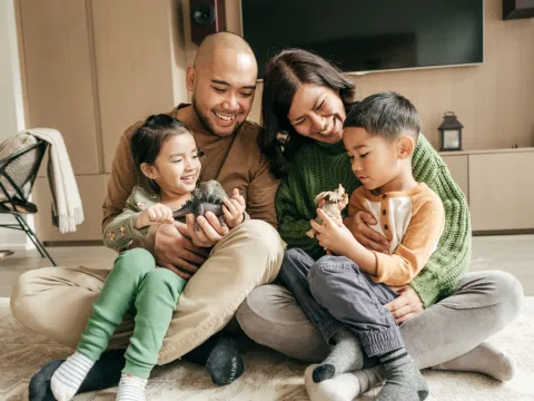 Happy family sitting on the floor in their living room.