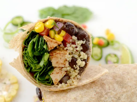 Half of Southwest chicken wrap lying on tortilla with jalapeno garnishes