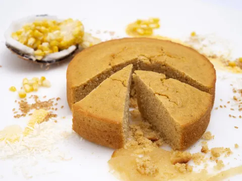 a round loaf of freshly baked cornbread, with two slices cut loose