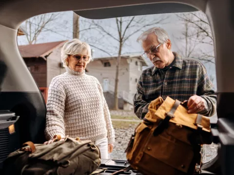 A senior couple packs their car to prepare for a hurricane.