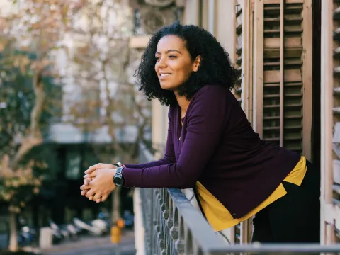 A woman enjoys fresh air on her balcony.