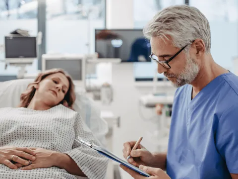 Woman in ER while doctor writes notes.