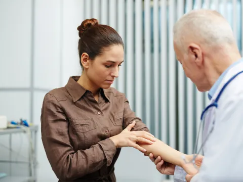A woman points to arm to show a doctor.