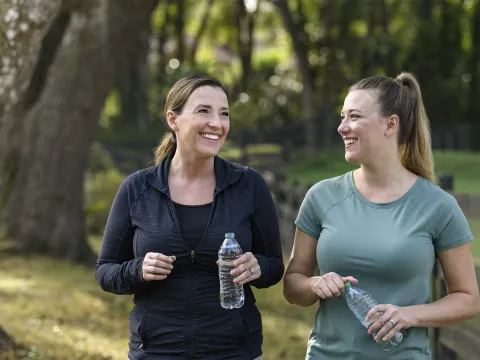 Two women holding water bottles walking together outside