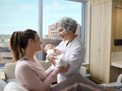 A midwife at an AdventHealth hospital hands a woman her baby.