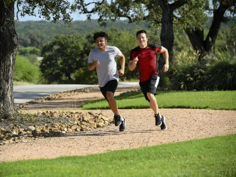 Two young men running outside on a path.