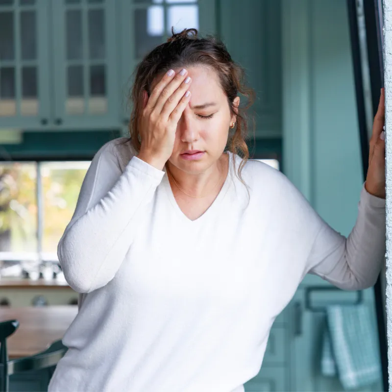 A Woman Holds Her Forehead with a Look of Pain on Her Face