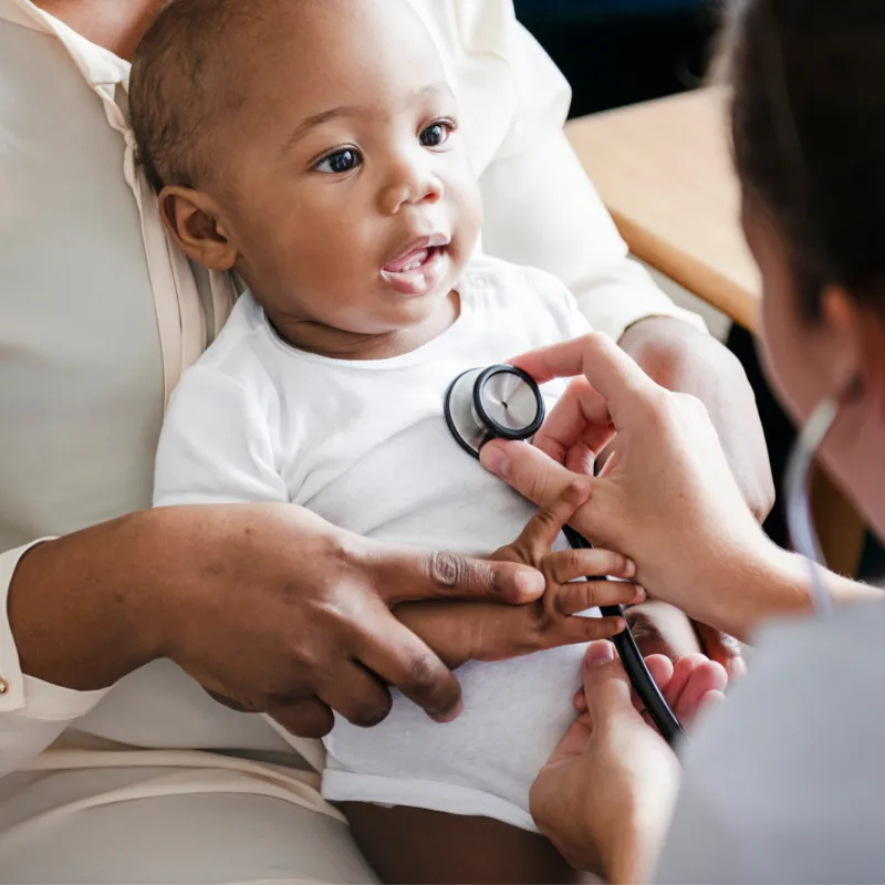 A Physician Checks a Smiling Baby's Breathing with a Stethoscope