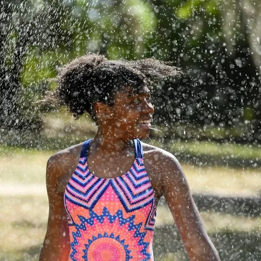 A tween plays in a sprinkler
