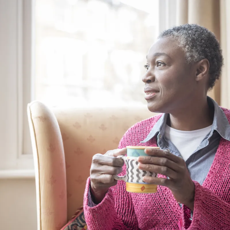 Enjoying her morning coffee, a mature woman reflects on life.