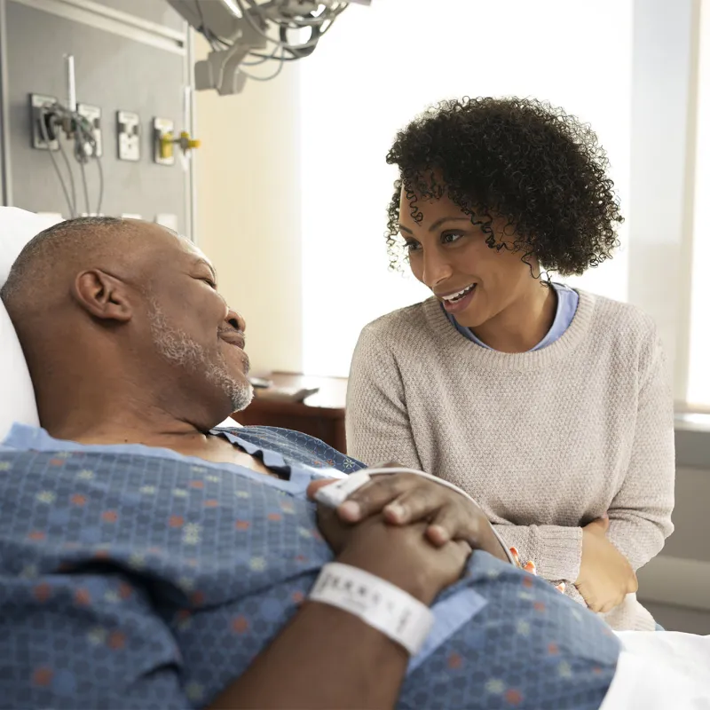 Family member comforting patient in hospital bed.