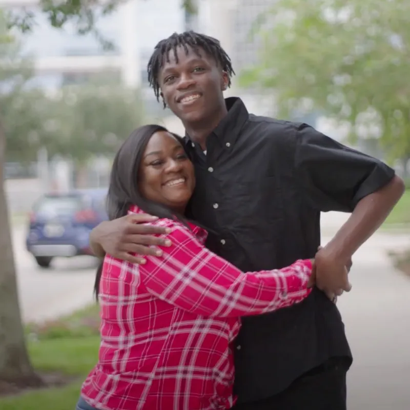 Antonio hugging his mother outside on a sidewalk.