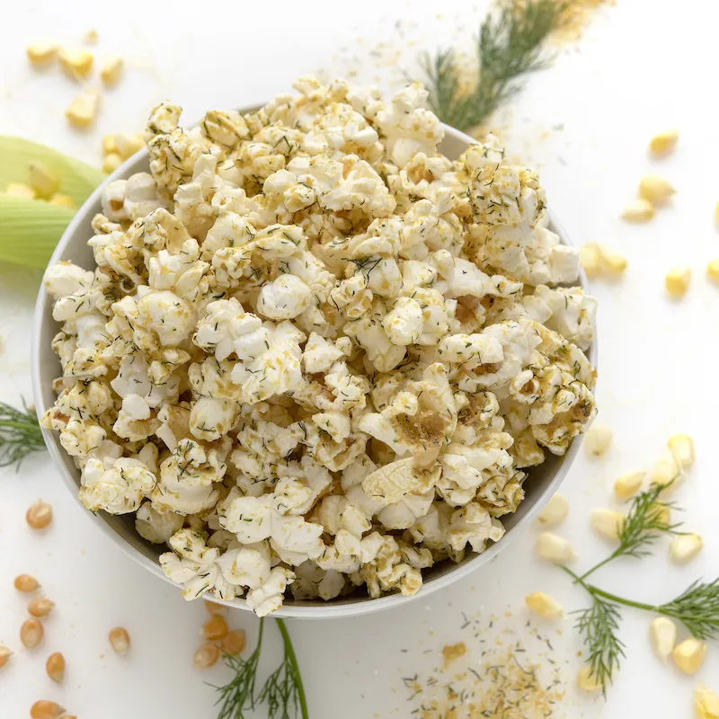 White bowl of seasoned popcorn on white counter