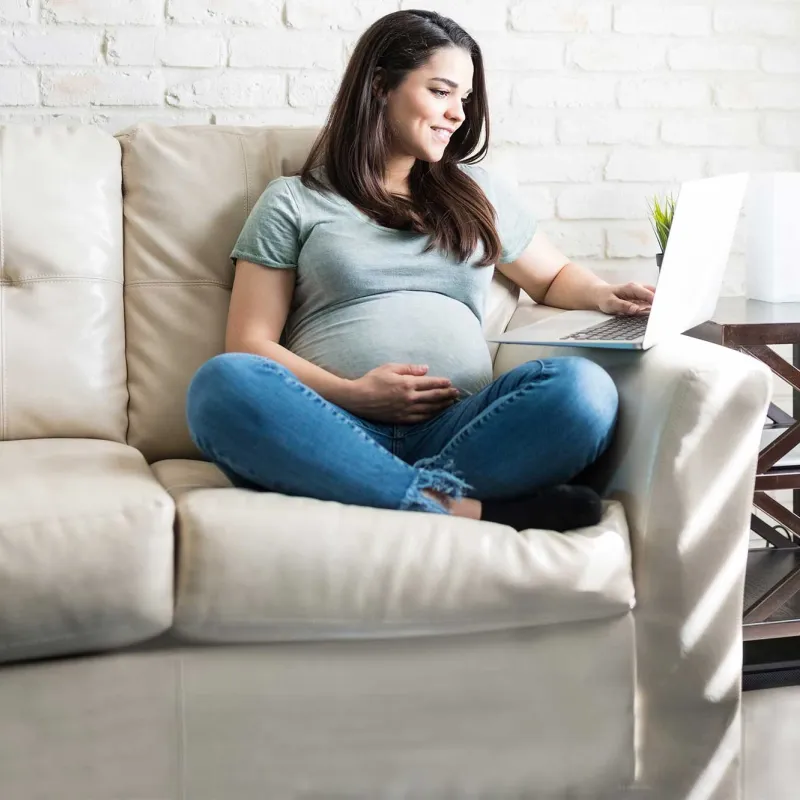 An expectant mother has a video call on her computer.