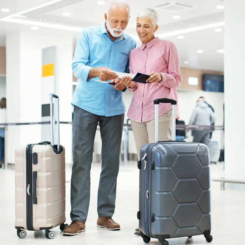 An older adult couple prepares to take a flight at the airport.