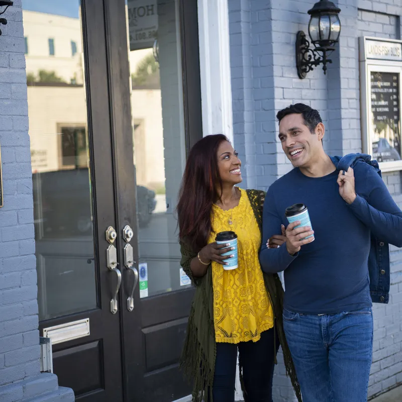 Hispanic Couple walking outdoors with coffee