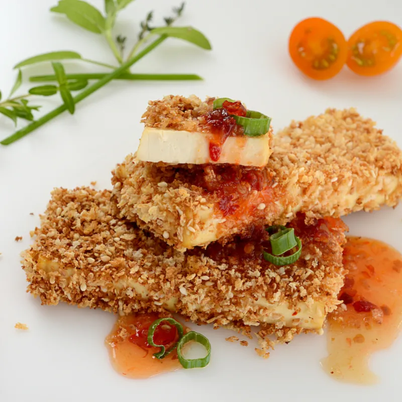 Two and a half crusted tofu steaks with herb and tomato garnishes