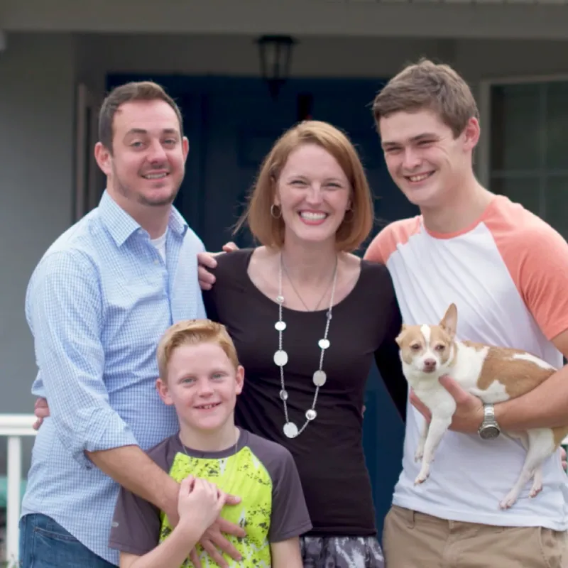 Family laughing in front of house