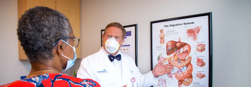 Allen Chudzinski showing patient diagram of digestive system while both are wearing masks at AdventHealth Digestive Institute Tampa.