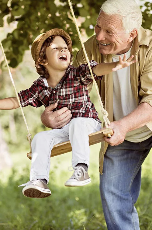 Grandfather pushes grandson on a tree swing