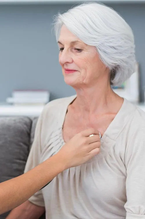 A nurse checks a patient's heart beat as they are both sitting down.
