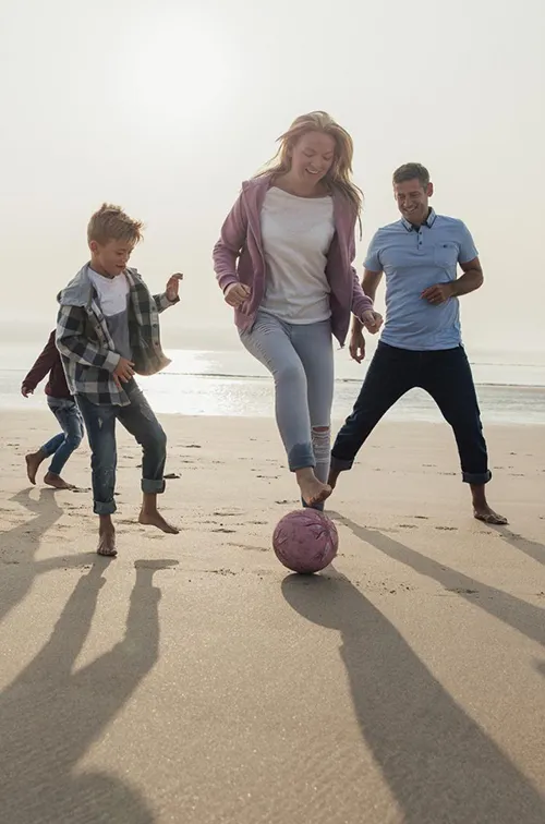 A family plays a friendly game of soccer on the beach