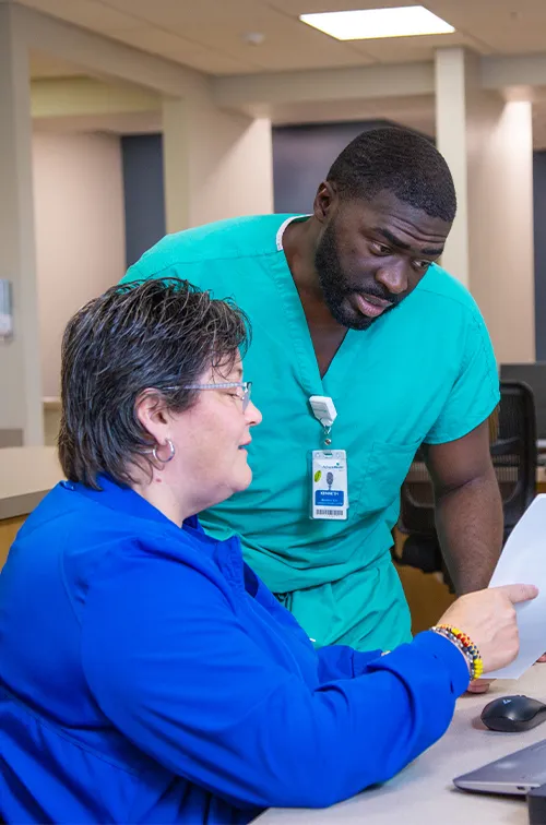 Two team members of AdventHealth Digestive Health Institute looking at a piece of paper and talking.