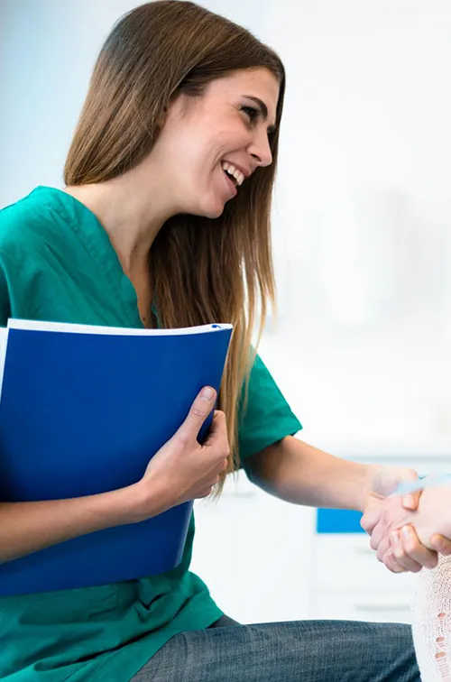 A woman in a lab, shaking hands with a lab tech after getting blood drawn.