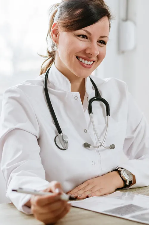 A friendly doctor meets a patient for the first time. They are both sitting at a desk, facing each other.