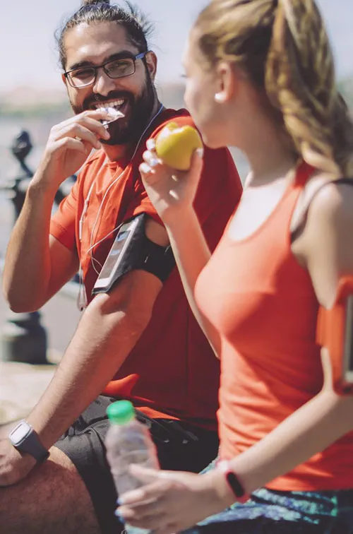 Two runners eat a healthy snack.