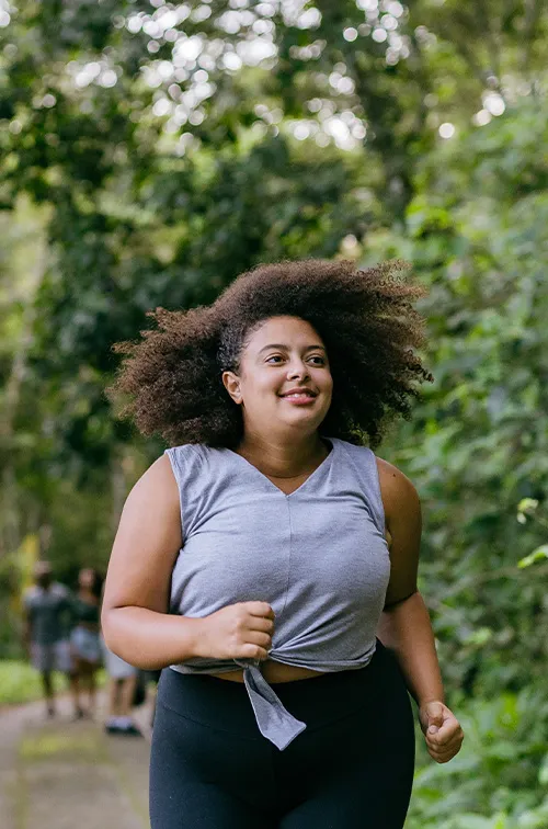 Hispanic woman running outdoors in a forest.