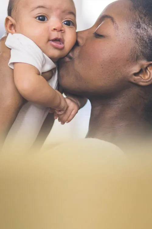 Mother holding and kissing her baby.