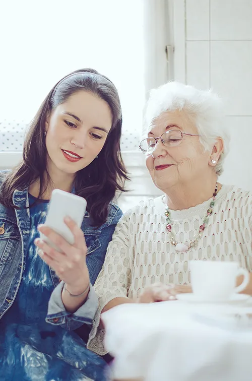 A young woman with an older women checking a cell phone