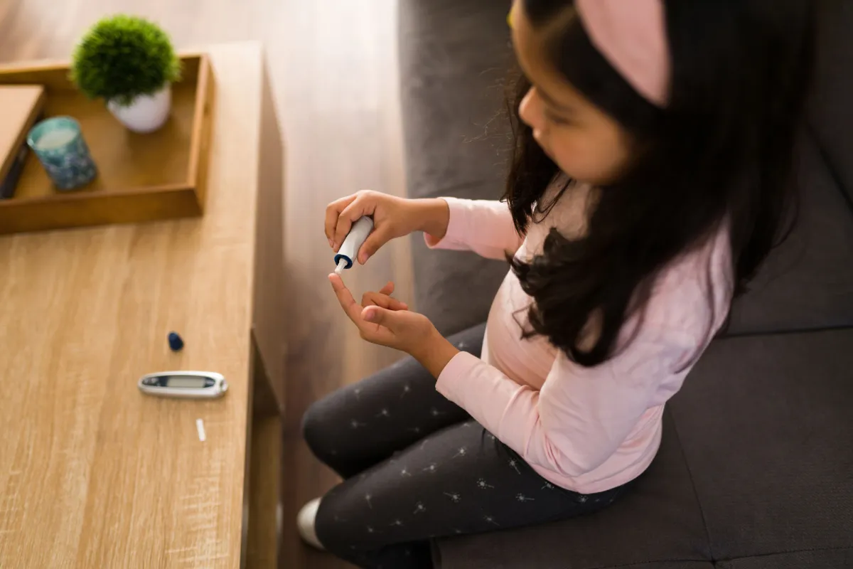 A little girl checking her sugar level using an at-home tester.
