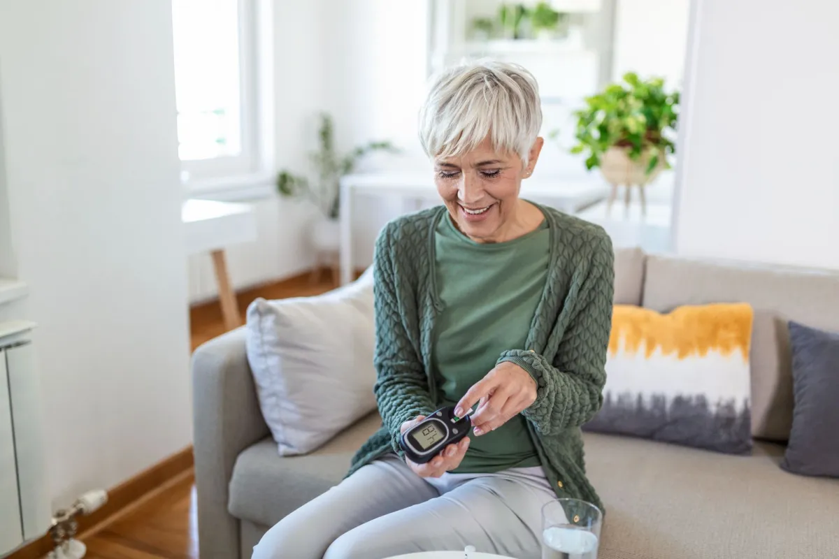 A mature woman taking an at-home diabetes test in her living room.