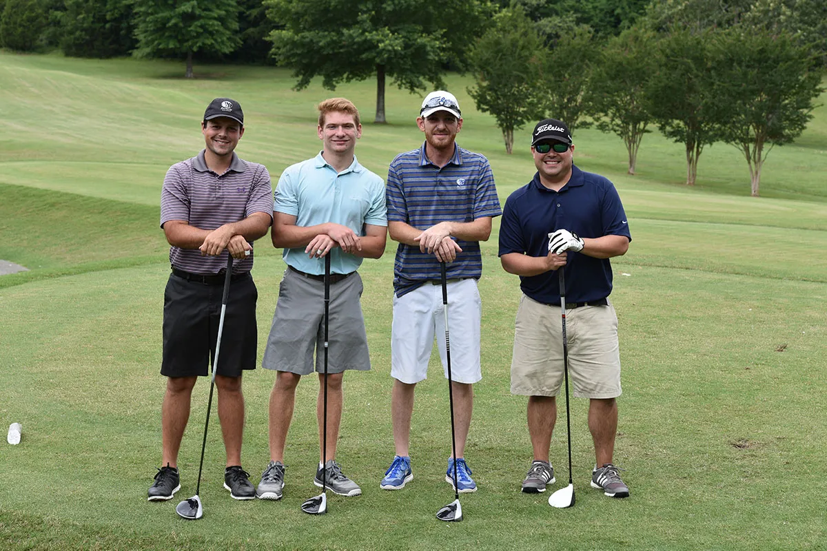 Group of golfers standing with golf clubs in hand.